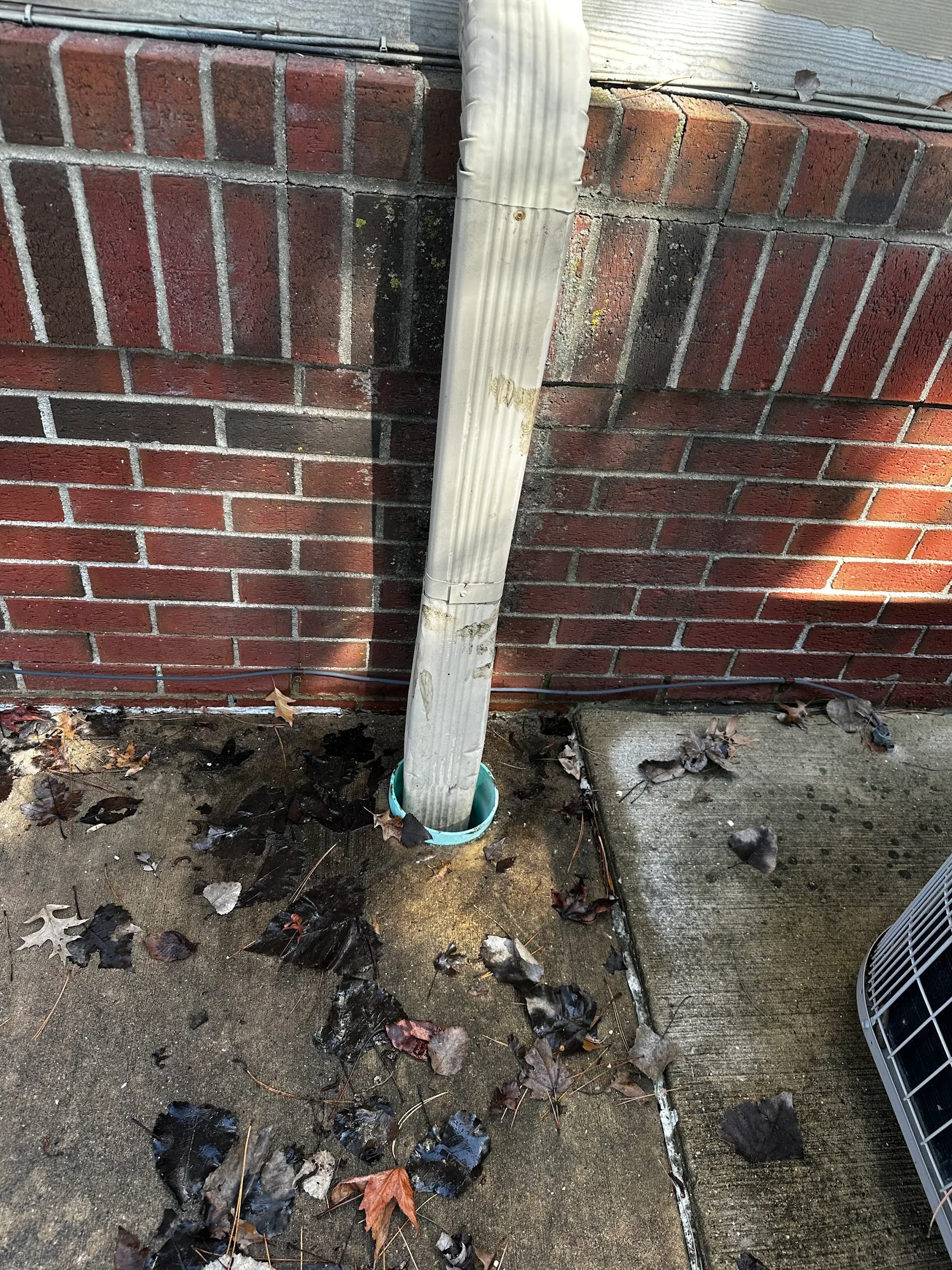Clean brick foundation with white downspout after pressure washing service