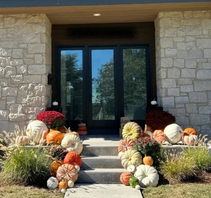 Clean stone facade and concrete steps at residential entryway with black triple-door entrance