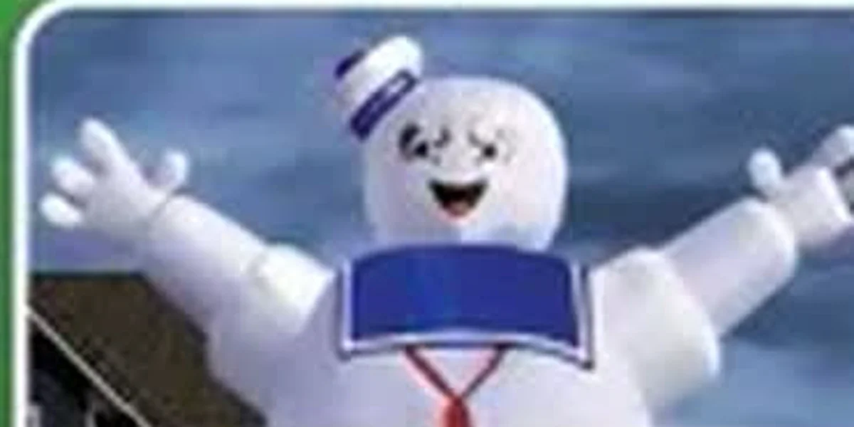Large illuminated Stay Puft Marshmallow Man inflatable decoration in front of a house at dusk with Halloween pumpkins in the yard